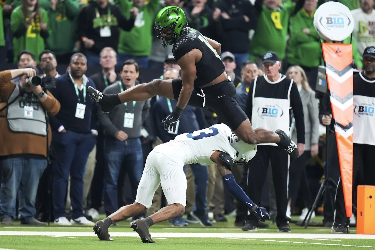Oregon tight end Kenyon Sadiq (18) leaps over Penn State cornerback Jalen Kimber (3) during a 28-yard touchdown reception in the first half of the Big Ten championship NCAA college football game, Saturday, Dec. 7, 2024, in Indianapolis. (AP Photo/AJ Mast)