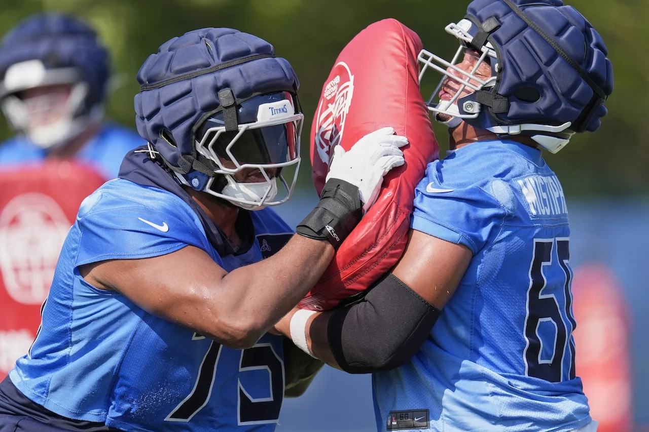 Tennessee Titans offensive tackle Dan Moore Jr., left, and offensive lineman Sam Mustipher, right, runs through a drill during practice at the team's NFL football training camp Thursday, July 24, 2025, in Nashville, Tenn. (AP Photo/George Walker IV)